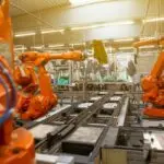 Braços robóticos industriais em uma linha de produção automatizada