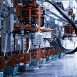 Linha de produção automatizada com máquinas, painéis de comando e cabos